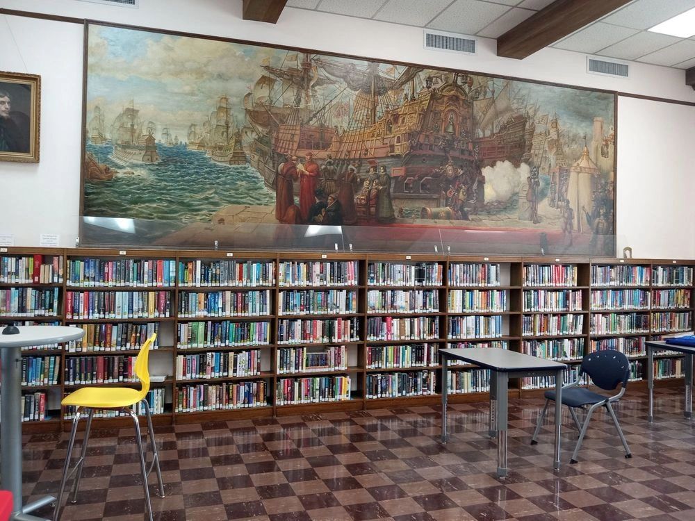 Lake Worth Beach Library reading room with historic maritime mural and floor-to-ceiling bookshelves